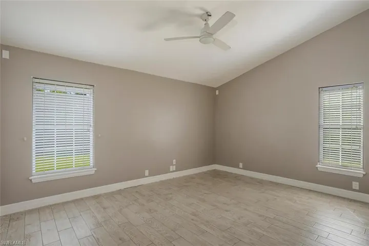 Unfurnished room with ceiling fan, a healthy amount of sunlight, lofted ceiling, and light hardwood / wood-style flooring