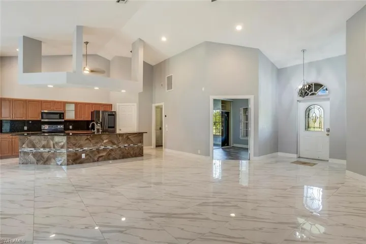 Kitchen featuring hanging light fixtures, stainless steel appliances, high vaulted ceiling, and tasteful backsplash