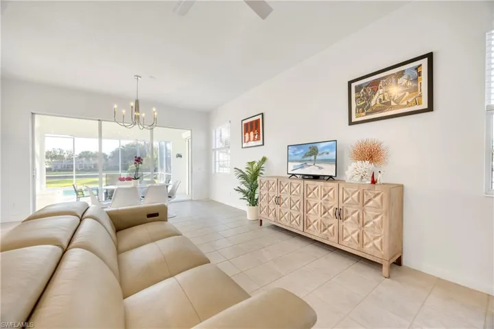 Living area with a chandelier, light tile patterned floors, and ceiling fan