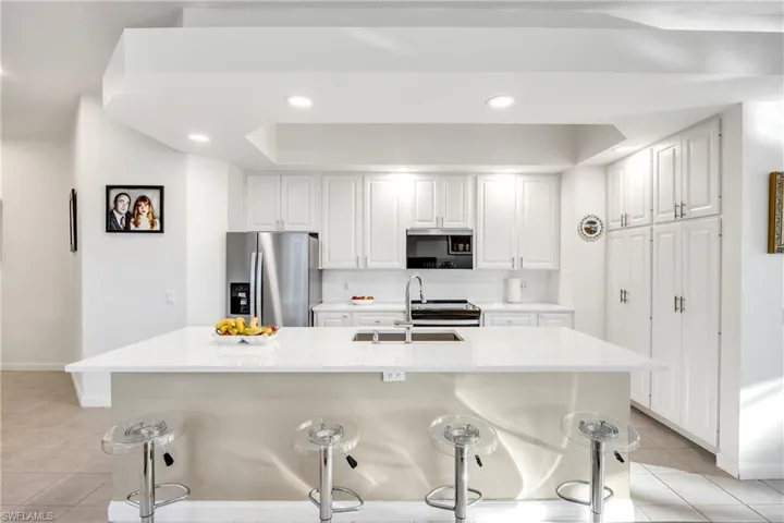 Kitchen featuring a kitchen breakfast bar, light tile patterned flooring, white cabinets, and recessed lighting