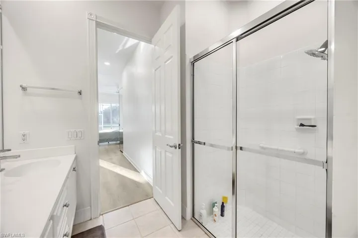 Full bathroom featuring a shower stall, vanity, and light tile patterned flooring