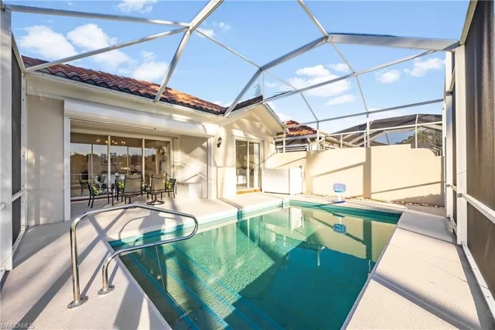 Swimming pool featuring a sunroom, glass enclosure, and a patio