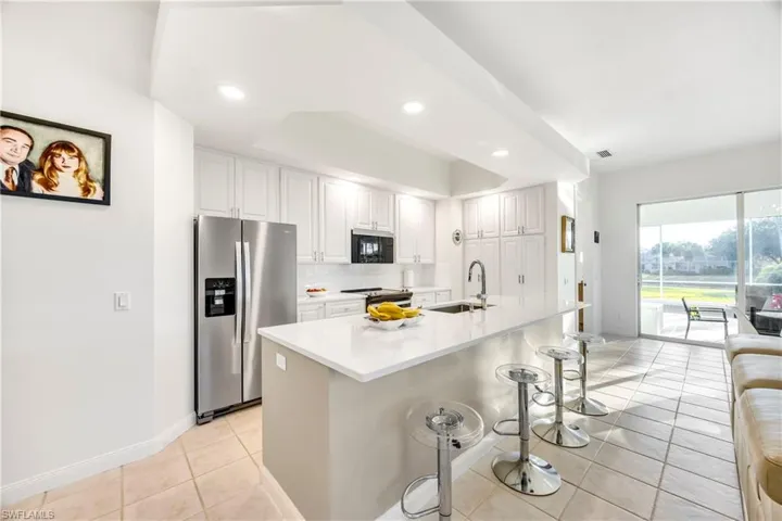 Kitchen with a breakfast bar, appliances with stainless steel finishes, a center island with sink, tasteful backsplash, and light tile patterned floors