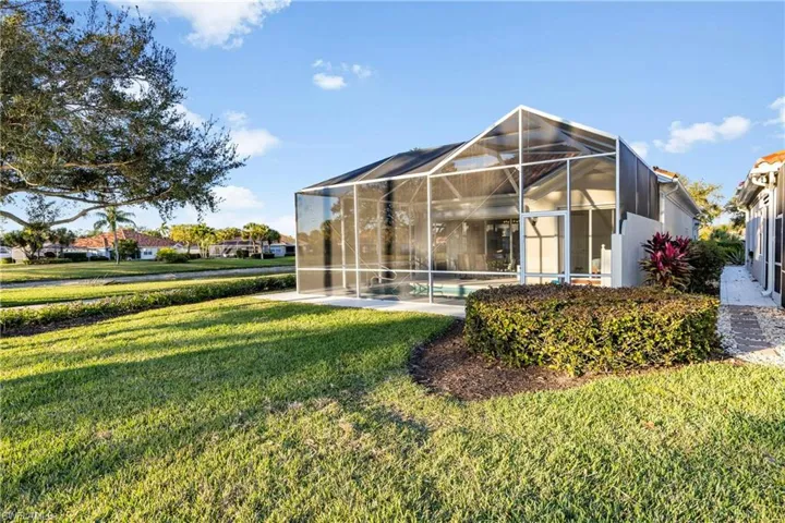 Back of property with a lanai, a sunroom, and a yard
