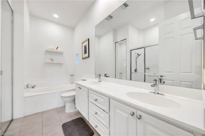 Bathroom featuring a stall shower, double vanity, a garden tub, light tile patterned flooring, and recessed lighting