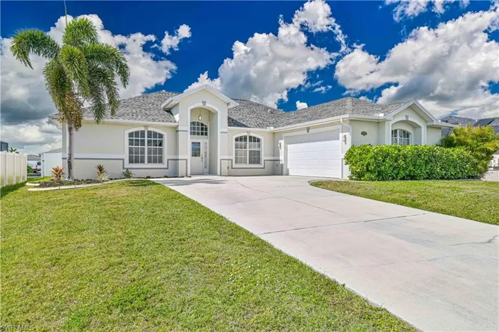 Ranch-style home with a front lawn, driveway, an attached garage, and stucco siding
