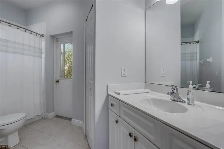 Bathroom featuring baseboards, toilet, tile patterned flooring, vanity, and a closet