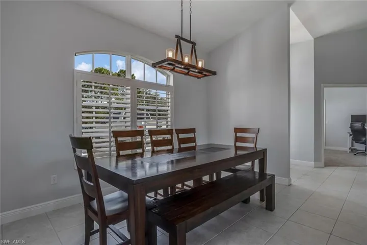Dining area featuring light tile patterned flooring, baseboards, and an inviting chandelier