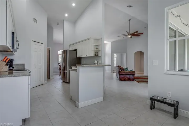 Kitchen featuring arched walkways, white cabinets, open floor plan, stainless steel appliances, and open shelves