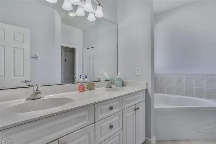 Full bath featuring double vanity, a sink, and a bath