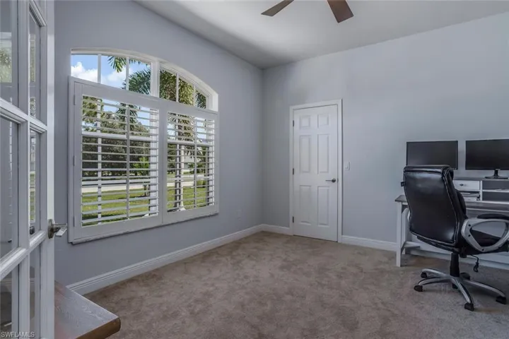 Office area with ceiling fan, baseboards, and light colored carpet