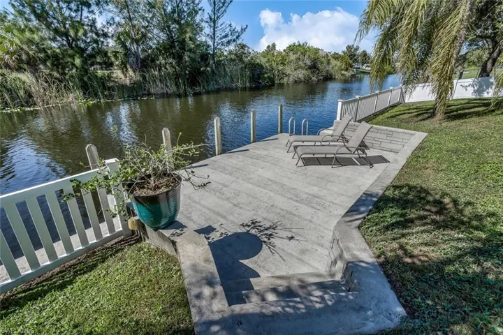 Dock area featuring a water view, fence, and a yard