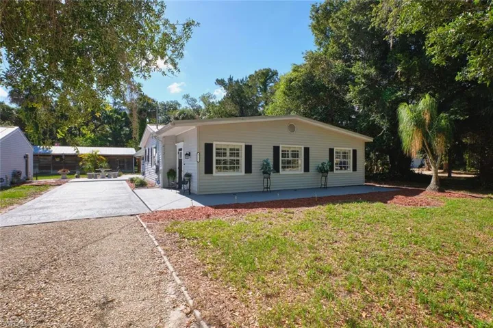 View of front facade featuring concrete driveway, a front yard, and a patio