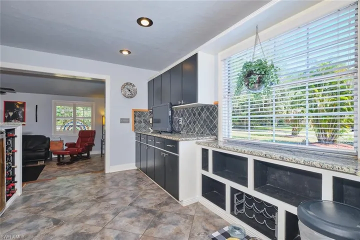 Kitchen featuring tasteful backsplash, baseboards, stone finish floors, open floor plan, and light stone countertops