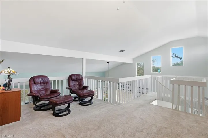 Sitting room featuring vaulted ceiling, carpet flooring, and an upstairs landing - Virtually Edited Image
