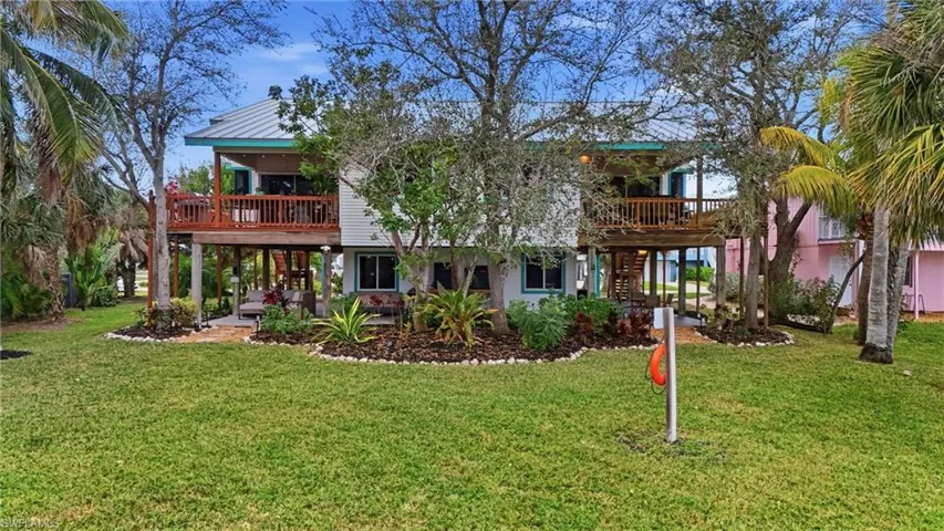 Rear view of house featuring a lawn and a deck - Virtually Edited Image