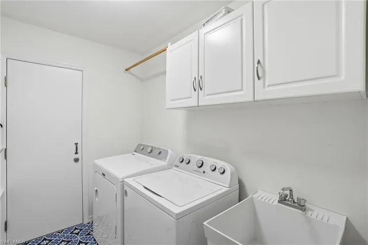 Laundry room featuring washing machine and clothes dryer and cabinet space - Virtually Edited Image