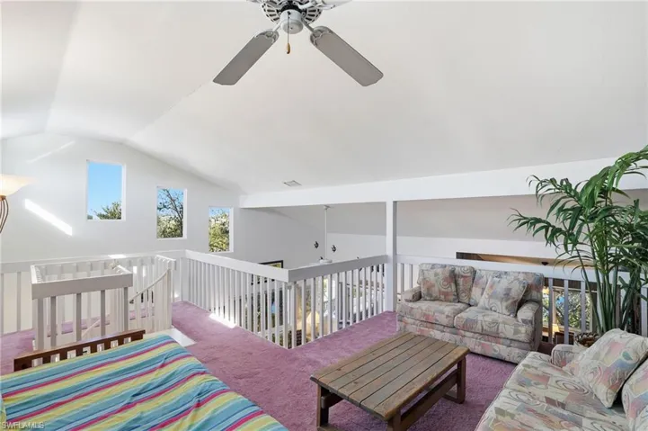 Carpeted living area featuring lofted ceiling and a ceiling fan - Virtually Edited Image