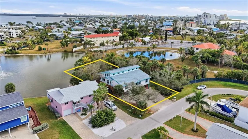 Aerial perspective of suburban area with a nearby body of water and property boundaries highlighted - Virtually Edited Image