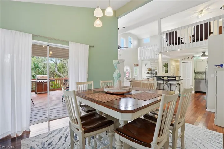 Dining area featuring ceiling fan, dark wood finished floors, and high vaulted ceiling - Virtually Edited Image