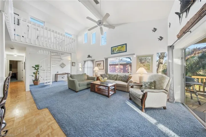 Living area with stairs, high vaulted ceiling, a ceiling fan, and beamed ceiling