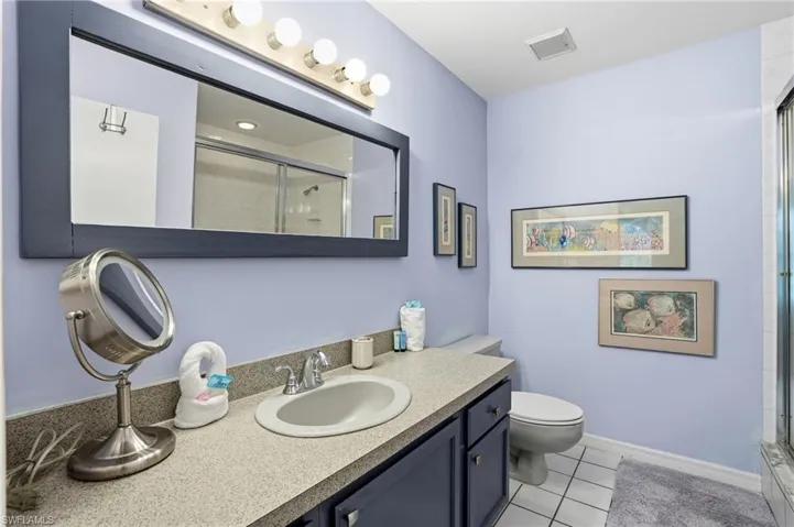 Full bathroom with vanity, light tile patterned floors, and a shower with shower door - Virtually Edited Image