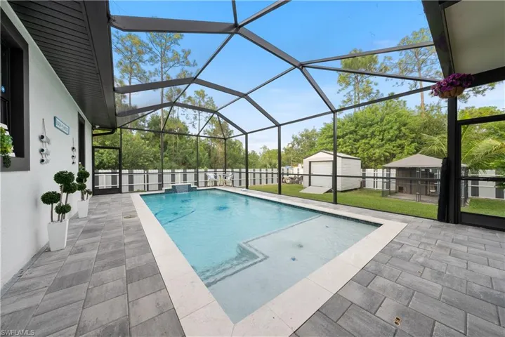 View of pool with a storage shed, a patio, a lanai, and a lawn