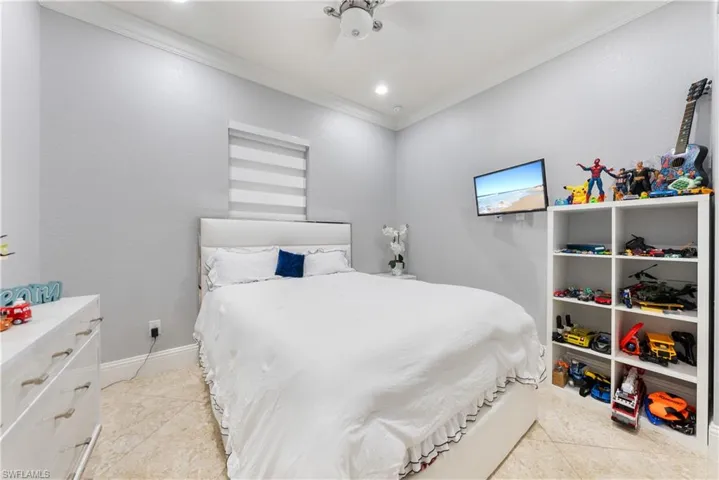 Tiled bedroom with ornamental molding and ceiling fan