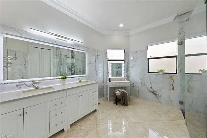 Bathroom featuring crown molding, tiled shower, and vanity