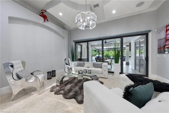 Living room with an inviting chandelier, a towering ceiling, and ornamental molding