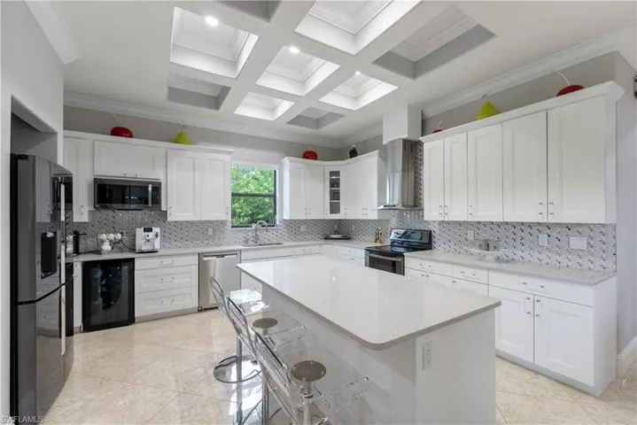 Kitchen featuring white cabinetry, wall chimney range hood, and stainless steel appliances