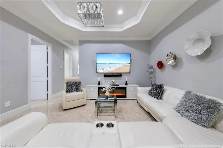 Tiled living room featuring a raised ceiling, a fireplace, and crown molding