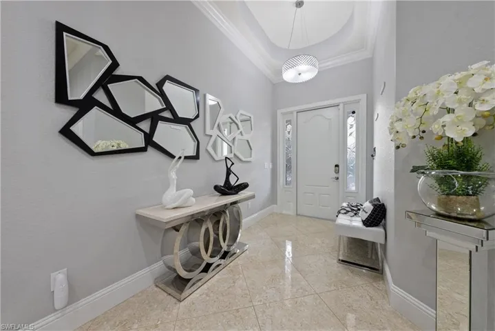 Foyer entrance featuring ornamental molding and a raised ceiling
