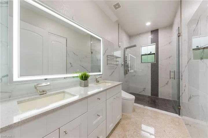 Bathroom featuring vanity, tile patterned flooring, toilet, and a shower with door