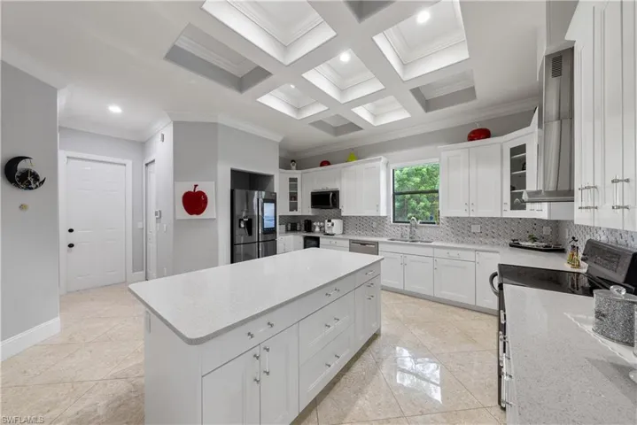 Kitchen with white cabinets, sink, stainless steel appliances, a center island, and crown molding