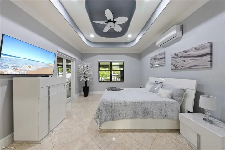 Tiled bedroom with a tray ceiling and a wall mounted air conditioner