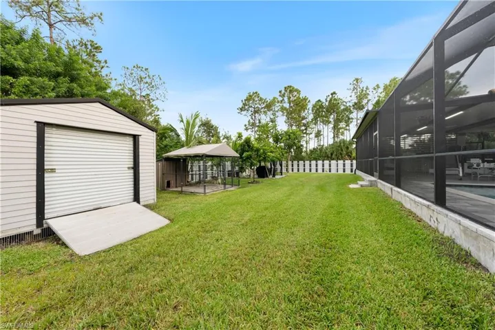 View of yard with an outdoor structure, glass enclosure, and a patio area