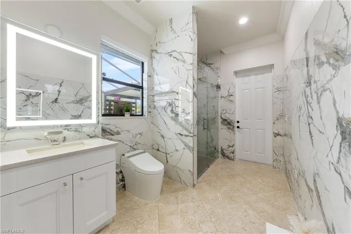 Bathroom featuring tile walls, vanity, crown molding, a shower with door, and toilet