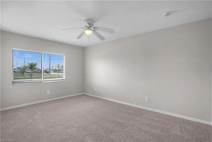 Bedroom featuring a window with horizontal blinds, overhead ceiling fan with lighting, light gray walls, and neutral-toned carpet flooring