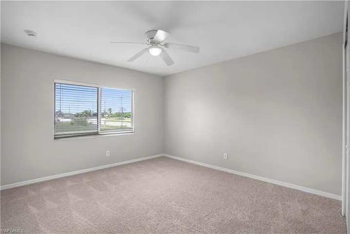 Bedroom featuring neutral carpeting and walls, a ceiling fan with integrated lighting, and a double window with horizontal blinds