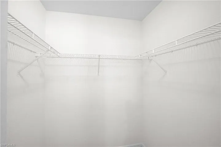Walk-in closet with white wire shelving and hanging rods