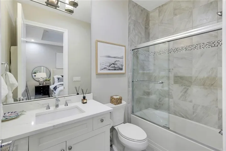 Full bathroom featuring toilet, bath / shower combo with glass door, and vanity