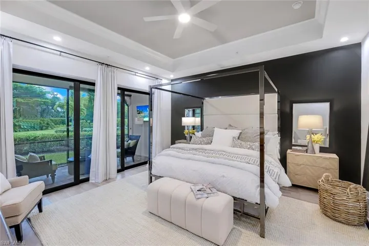 Primary Bedroom with hardwood / wood-style floors, a tray ceiling, access to outside, and ceiling fan