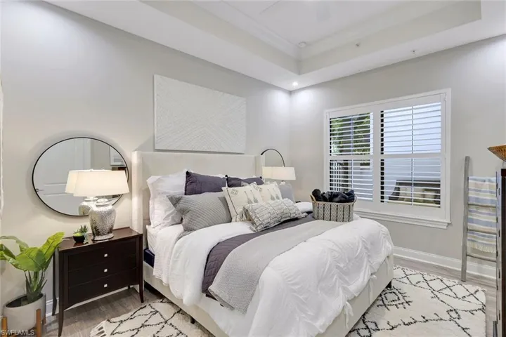 Bedroom featuring ceiling fan, a raised ceiling, and light hardwood / wood-style flooring