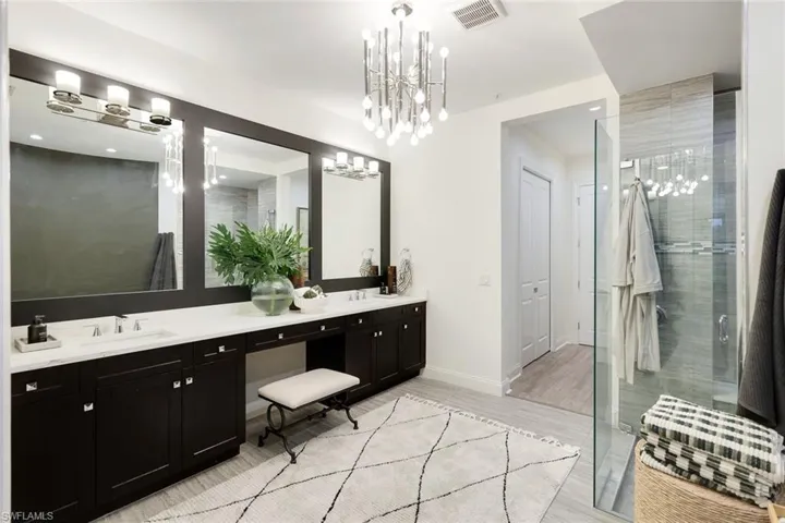 Primary Bathroom with vanity, dual sinks, tile floors, a shower with door, a chandelier, and vanity