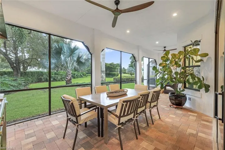 Outdoor screened in lanai featuring dining table and chairs and ceiling fan