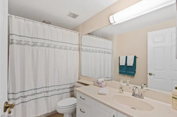 Bathroom featuring vanity, curtained shower, and toilet