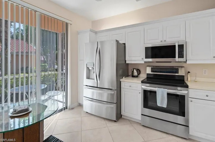 Kitchen with white cabinetry, stainless steel appliances, and light tile patterned flooring