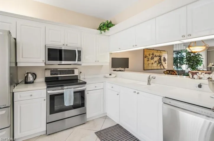 Kitchen featuring white cabinets, kitchen peninsula, stainless steel appliances, and light tile patterned floors
