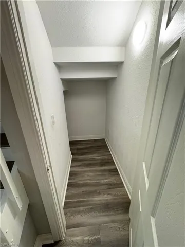 Stair Closet featuring a textured wall, wood finished floors, and baseboards
